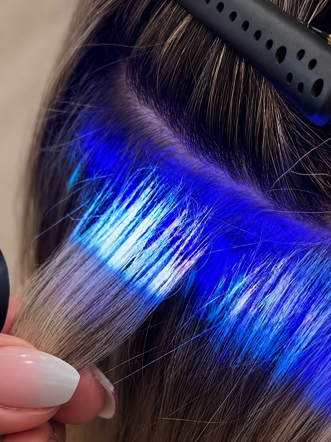 Hairdresser applying hair extensions with UV light using the EHE LIGHT™ system